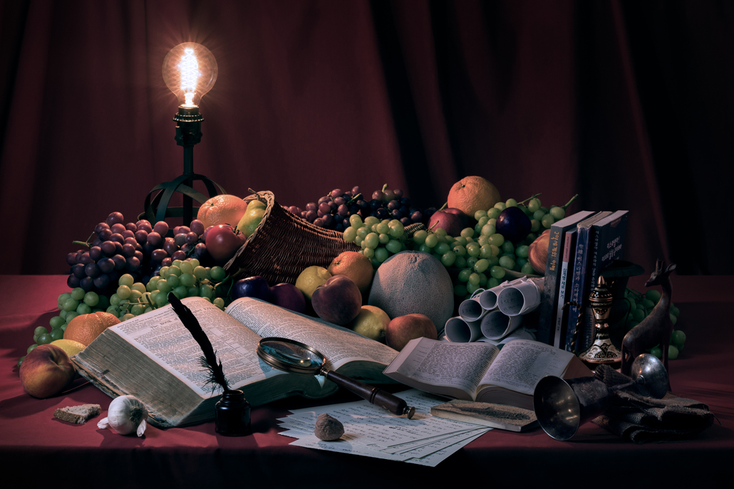 ﻿Still life photograph of books, fruit, and a light arranged on a desk